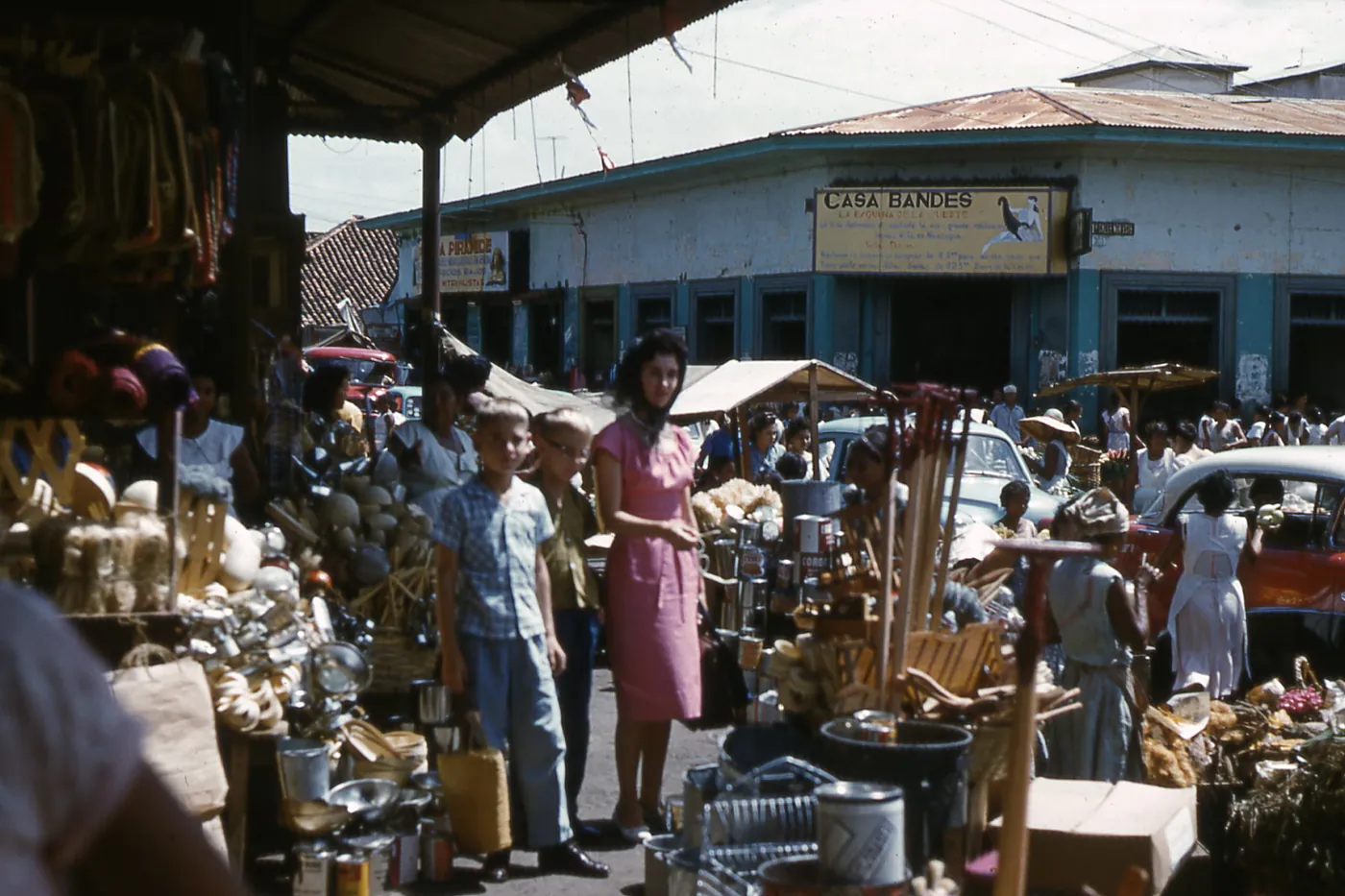 Busy market stalls under awnings with shoppers and goods